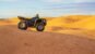 Quadracycle stands among the yellow sand dunes in the Sahara desert under the blue sky in Tunisia. Desert quad bike racing. Travel landscape with copy space