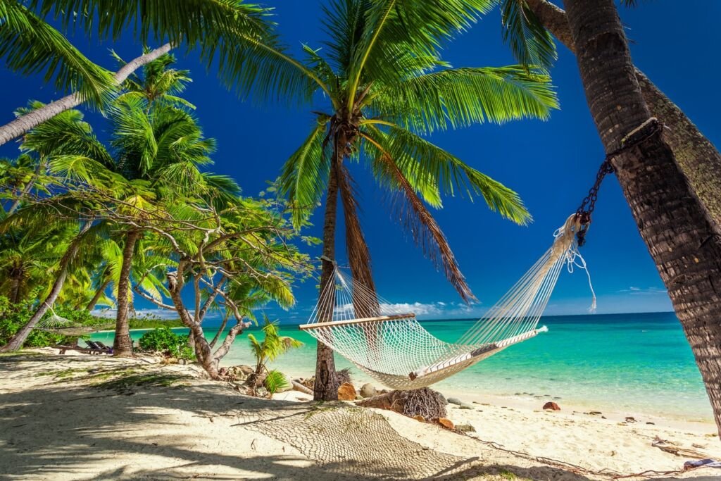 Empty hammock in the shade of palm trees on tropical Fiji Islands