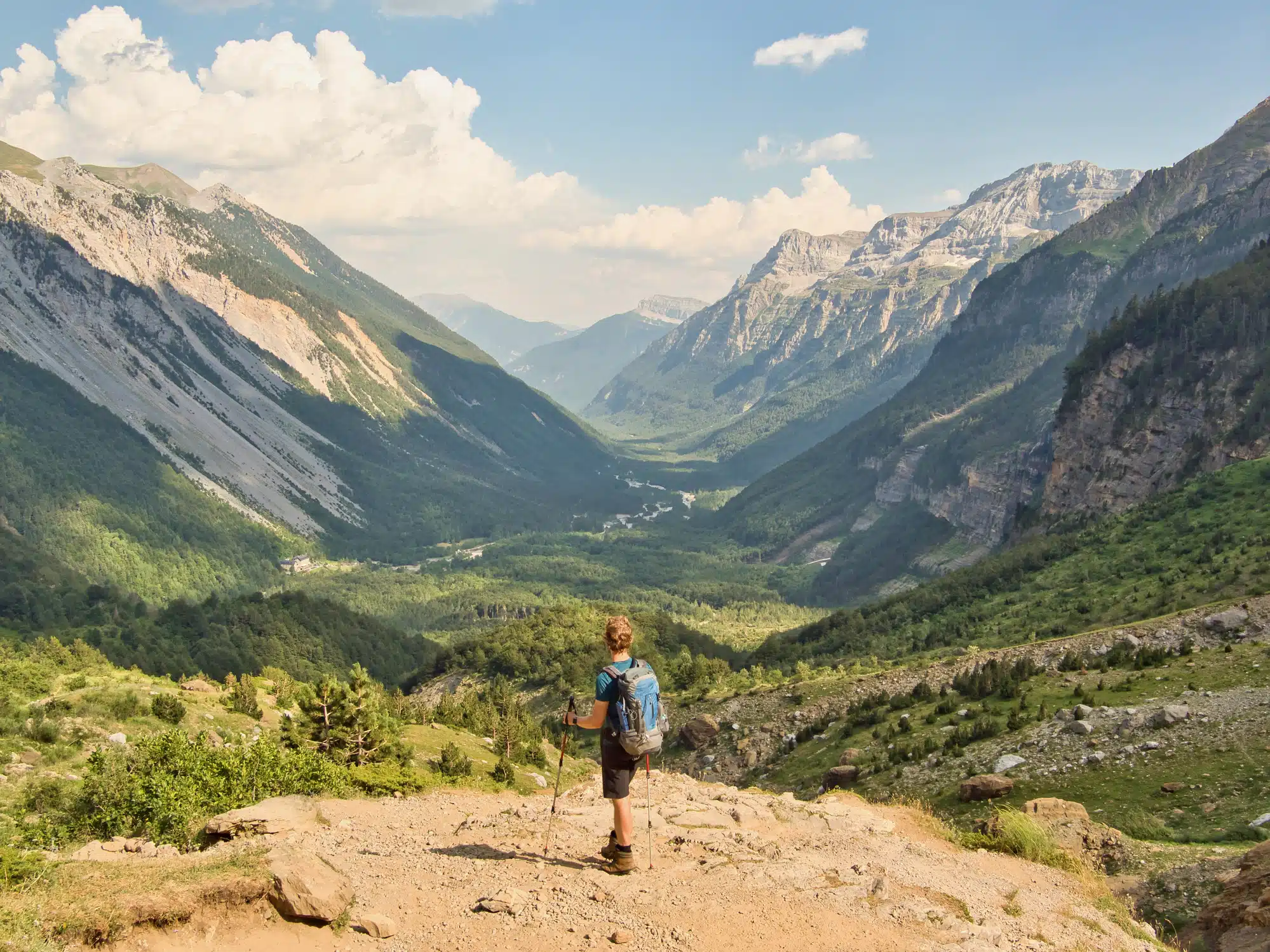 A young man enjoys the view of the mighty mountains of Valle de Pineta in the Spanish Pyrenees