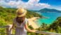Woman traveler wearing blue dress and straw hat at Panoramic aerial view of Laem Sing beach on Phuket island, Thailand in a sunny day