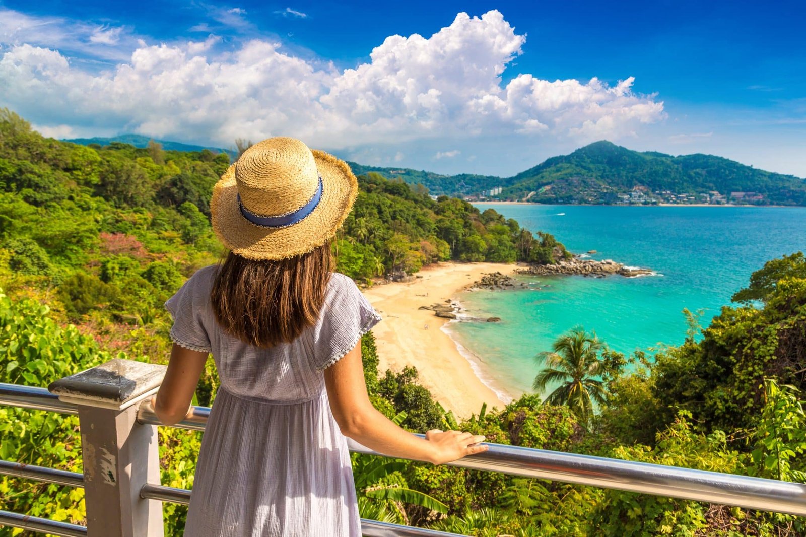 Woman traveler wearing blue dress and straw hat at Panoramic aerial view of Laem Sing beach on Phuket island, Thailand in a sunny day