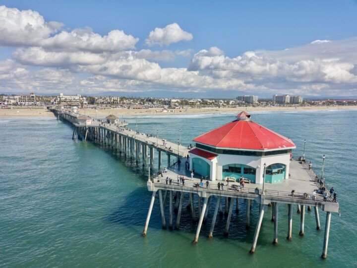 Aerial drone view of the Huntington Beach Pier against blue sky with clouds