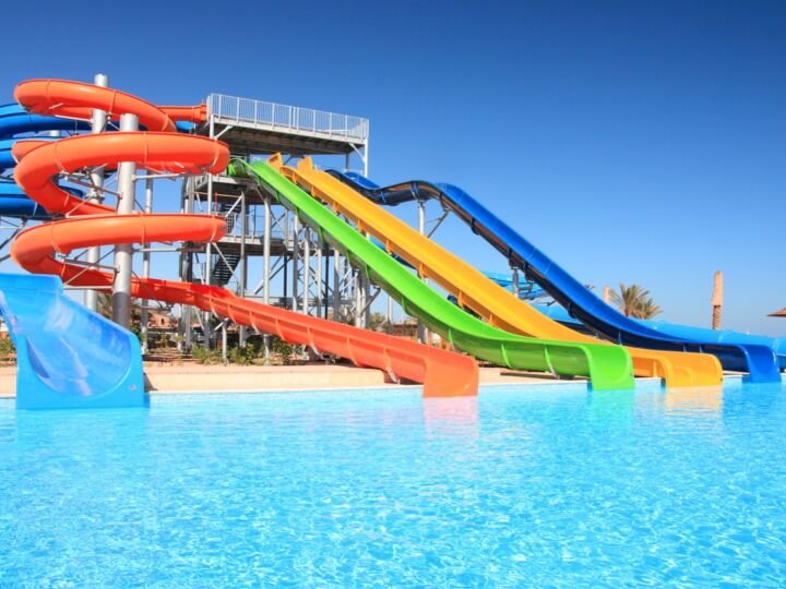 Colorful waterpark tubes and pool in tropical aquapark.