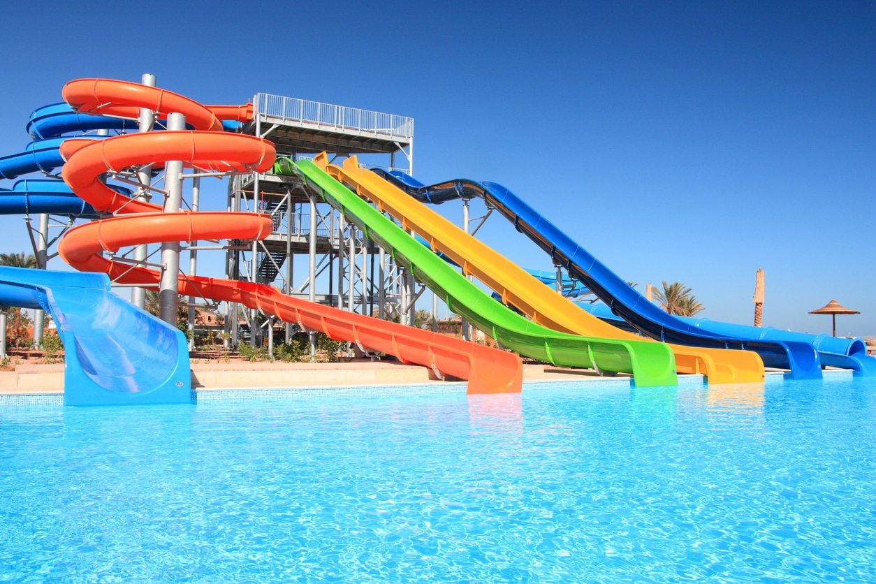 Colorful waterpark tubes and pool in tropical aquapark.