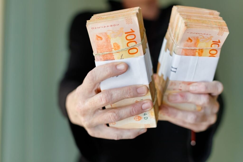 Macro closeup of bundles of 1000 Argentine peso bills held by woman's hands