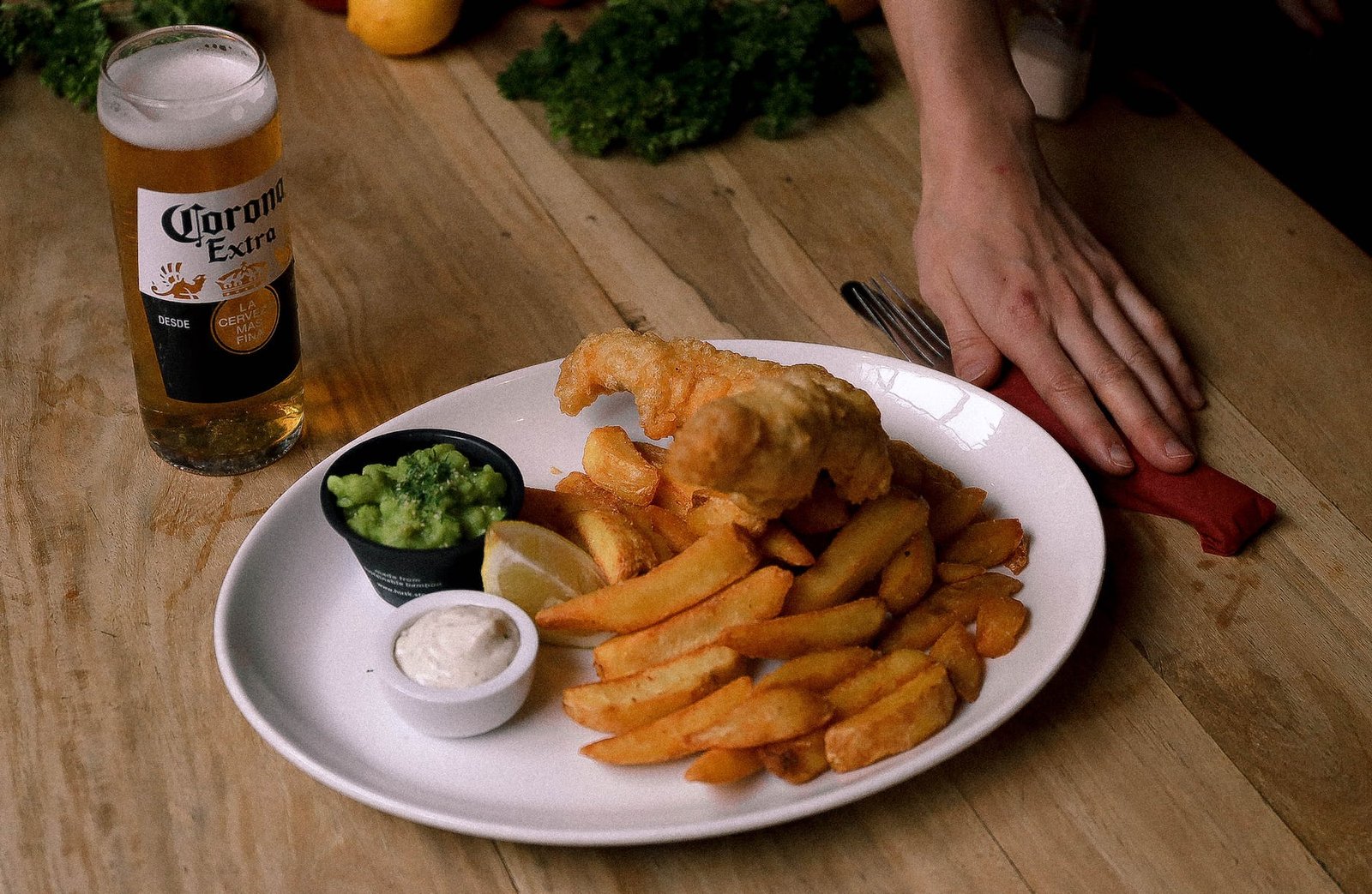 fish and chips on the white plate beside the glass of beer