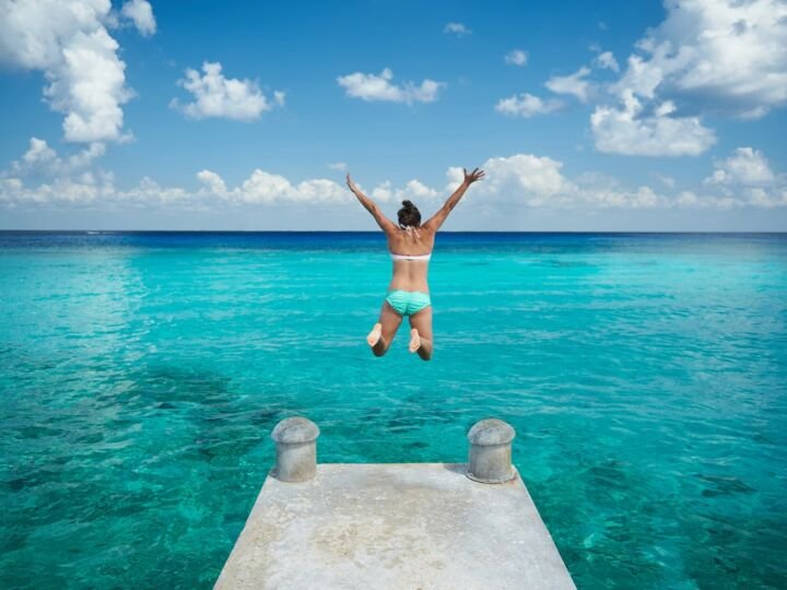 One woman jumping into blue water