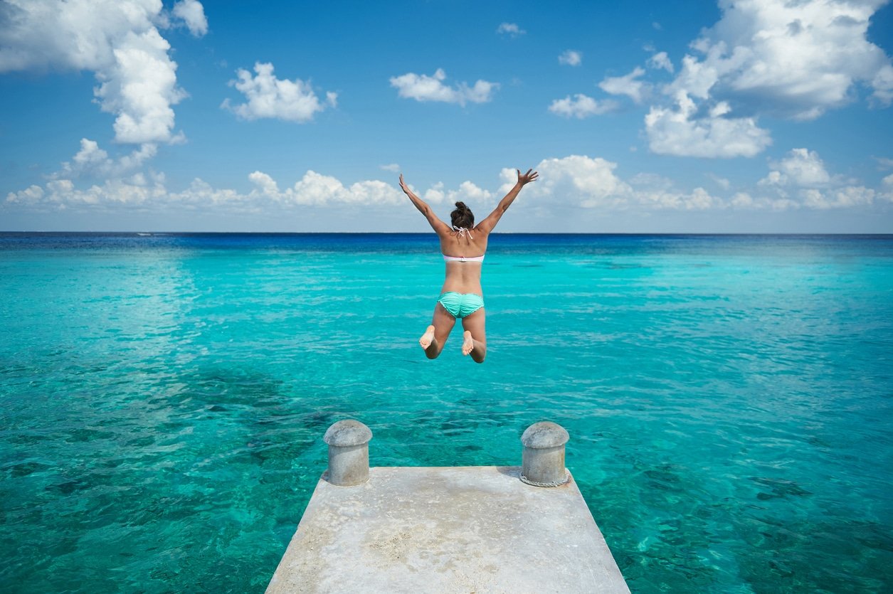 One woman jumping into blue water