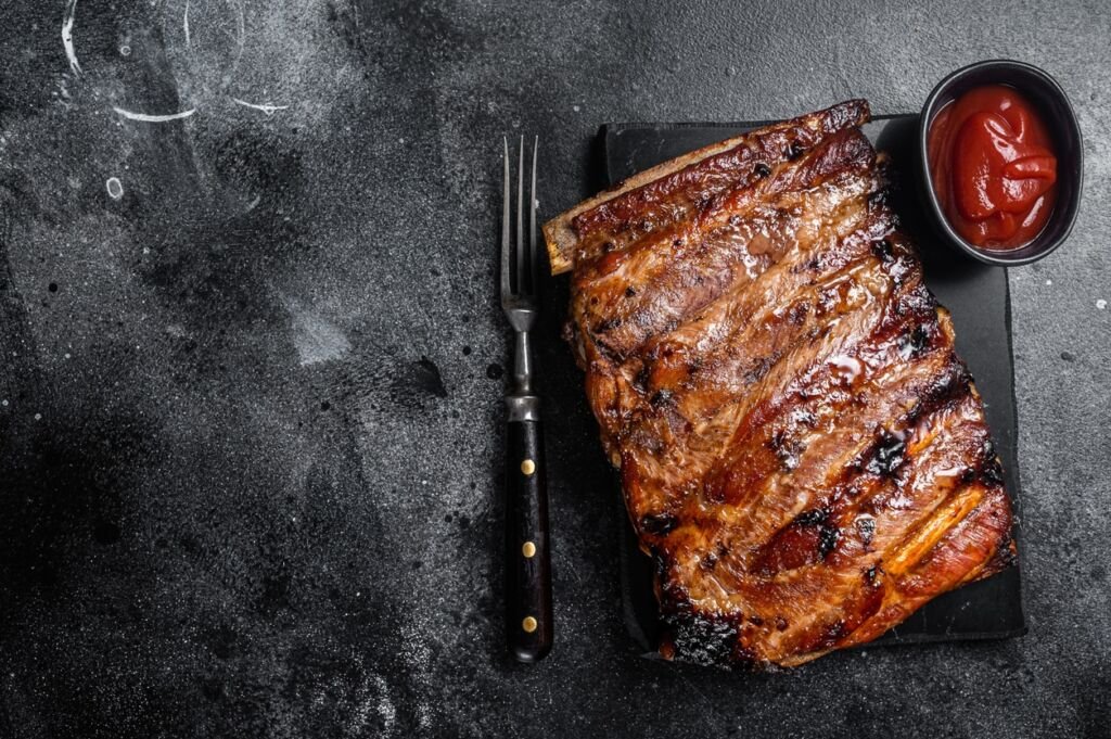 Full rack of BBQ grilled pork spare ribs on a marble board