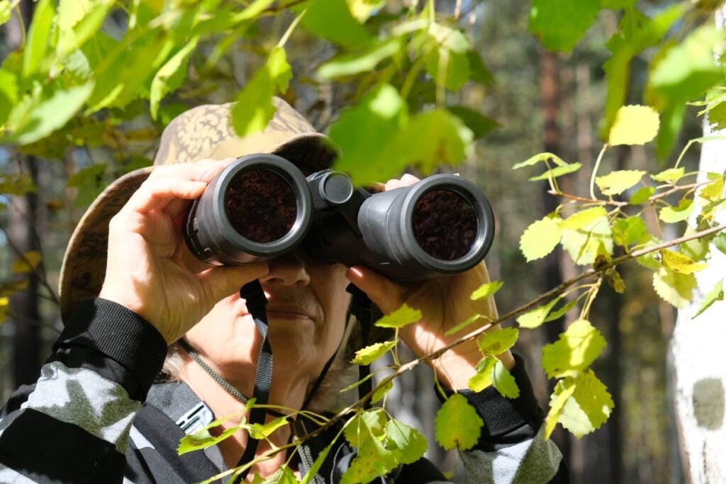 Active senior woman with binoculars in the forest