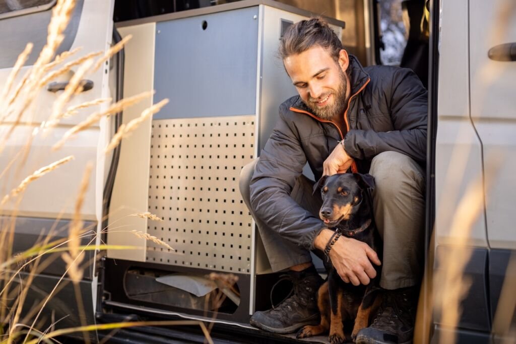 Man and his pet dog sitting in the doorway of a camper van