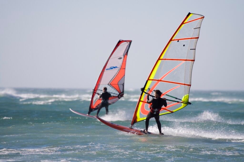 Two windsurfers on the water in wetsuits