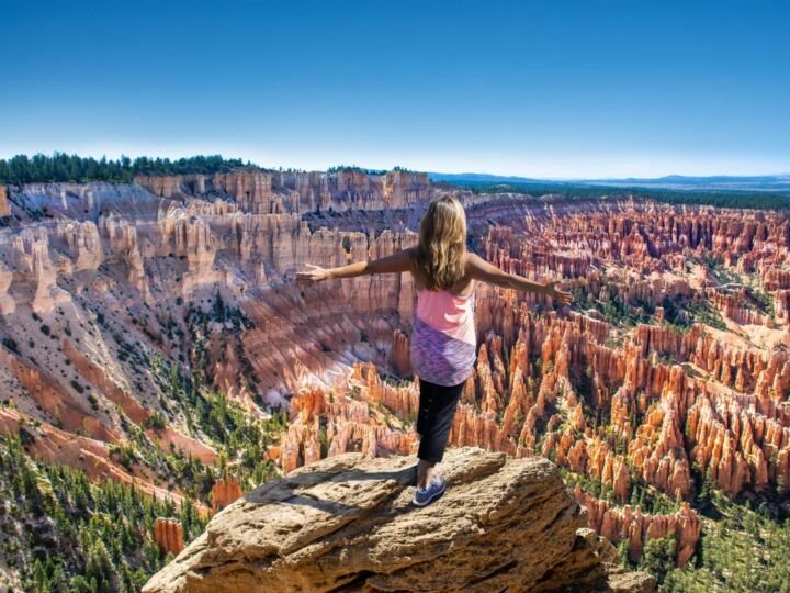 Hiker girl on the mountain top, сoncept of freedom, victory, active lifestyle. Woman relaxing on top of the mountain looking at beautiful mountain view. Woman with outstretched arms enjoying beautiful scenery on hiking trip. Inspiration Point, Bryce Canyon National Park, Utah, USA