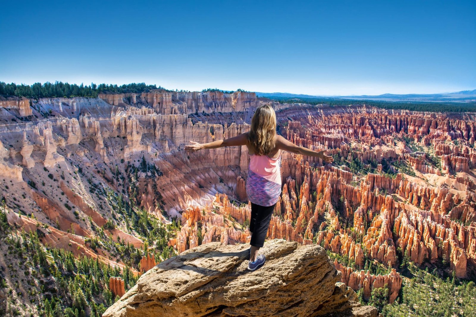 Hiker girl on the mountain top, сoncept of freedom, victory, active lifestyle. Woman relaxing on top of the mountain looking at beautiful mountain view. Woman with outstretched arms enjoying beautiful scenery on hiking trip. Inspiration Point, Bryce Canyon National Park, Utah, USA