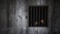 Hands of the prisoner on rusty bar of window and old grungy prison cell wall, concept of justice and horror