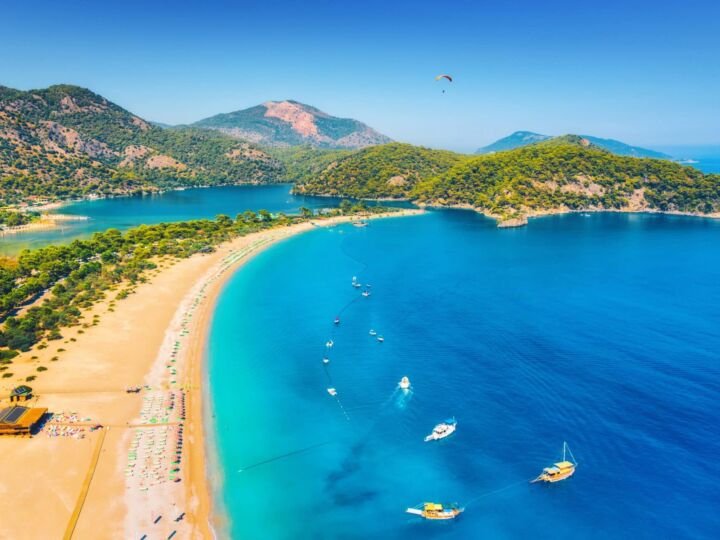 Amazing aerial view of Blue Lagoon in Oludeniz, Turkey. Summer landscape with sea spit, boats and yachts, green trees, azure water, sandy beach in sunny day. Travel. Top view of national park. Nature