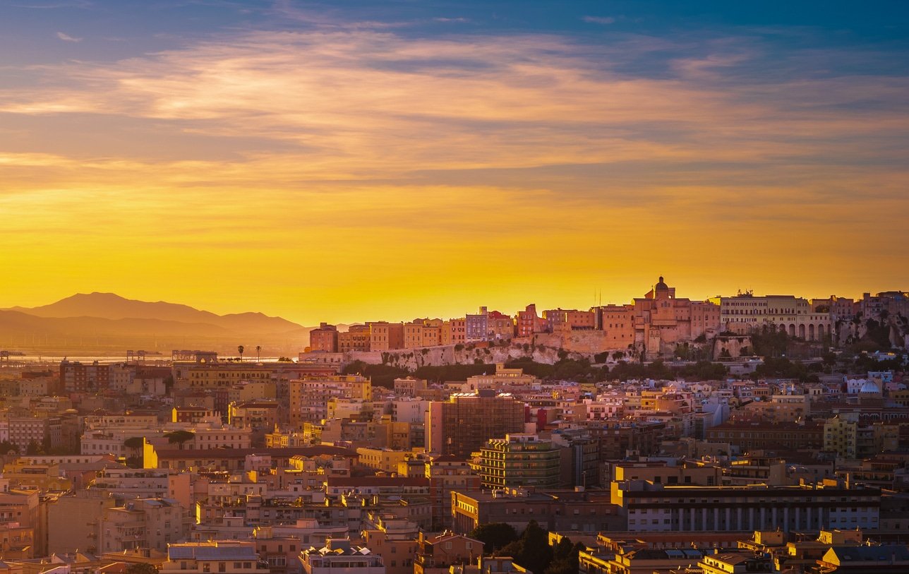 Sunset on Cagliari, panorama of the old city center with traditional colored houses with beautiful yellow-pink clouds, Sardinia Island, Italy