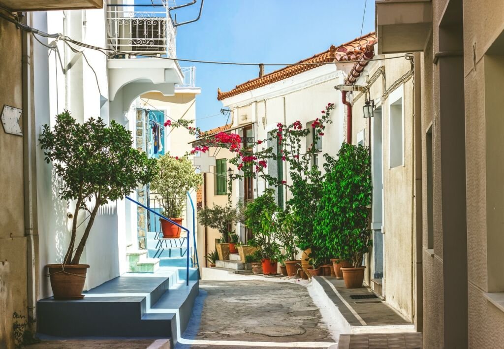 Narrow streets of Neorio town in Poros island, Greece;  Old white houses with flowers