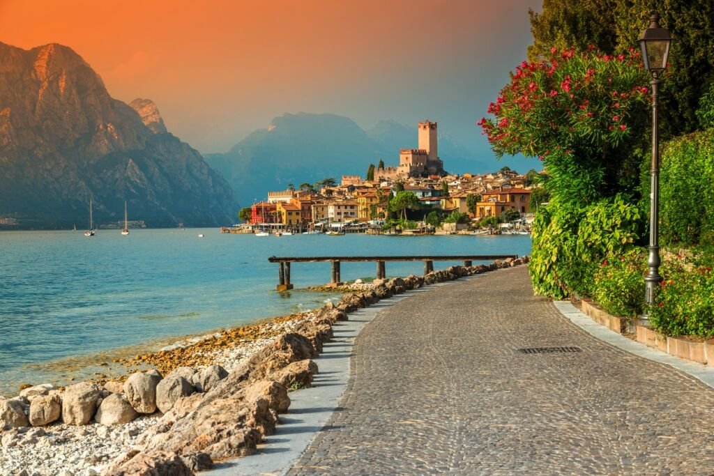Famous Malcesine touristic recreation resort, paved walkway with colorful flowers and stunning sunset, Garda lake, Veneto region, Italy, Europe
