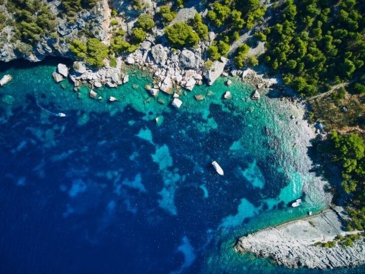 Drone view of a small, secluded cove beach in Croatia. Different kinds of blue in water, grey rocks