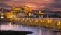 Cordoba - The Roman bridge and gate with the Cathedral in the background at evening dusk