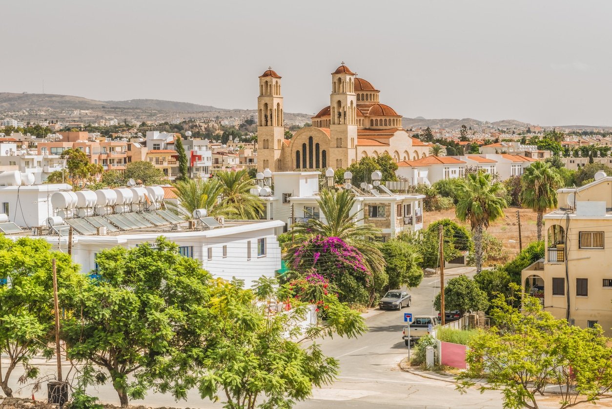 View of the city of Paphos, Cyprus. Trees in foreground, buildings in middle and hill in the back