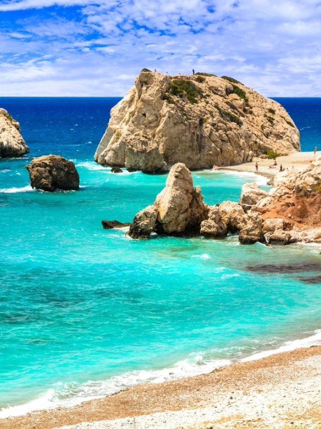 Beach in Cyprus with rock formations in the background, blue-hued water and beach