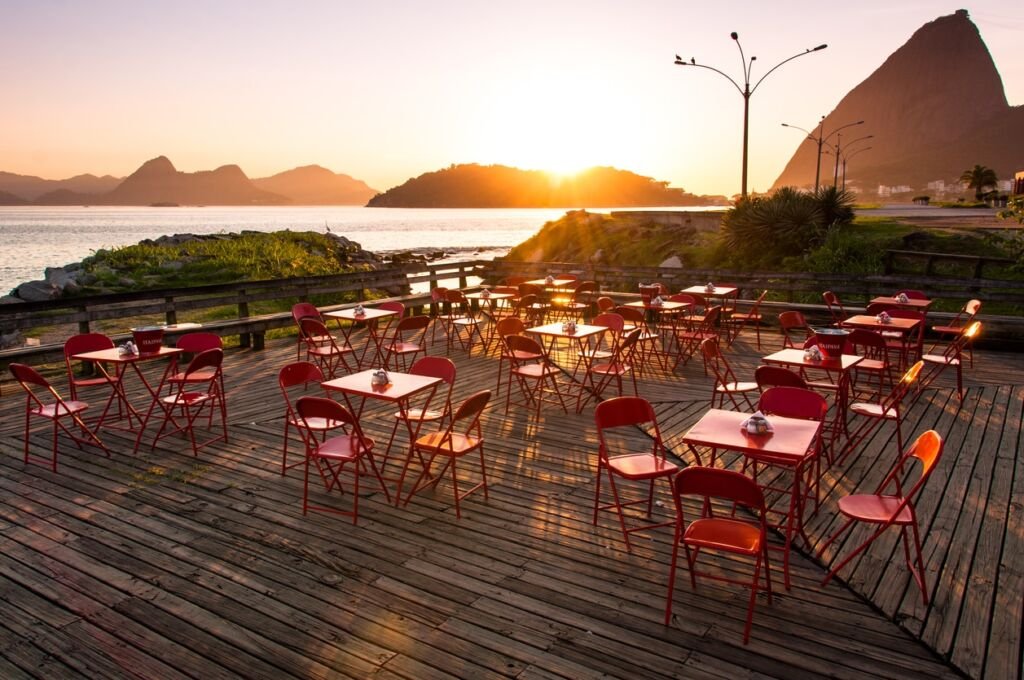 Red Chairs and Tables by Sunrise with the Sugarloaf Mountain in the Horizon.