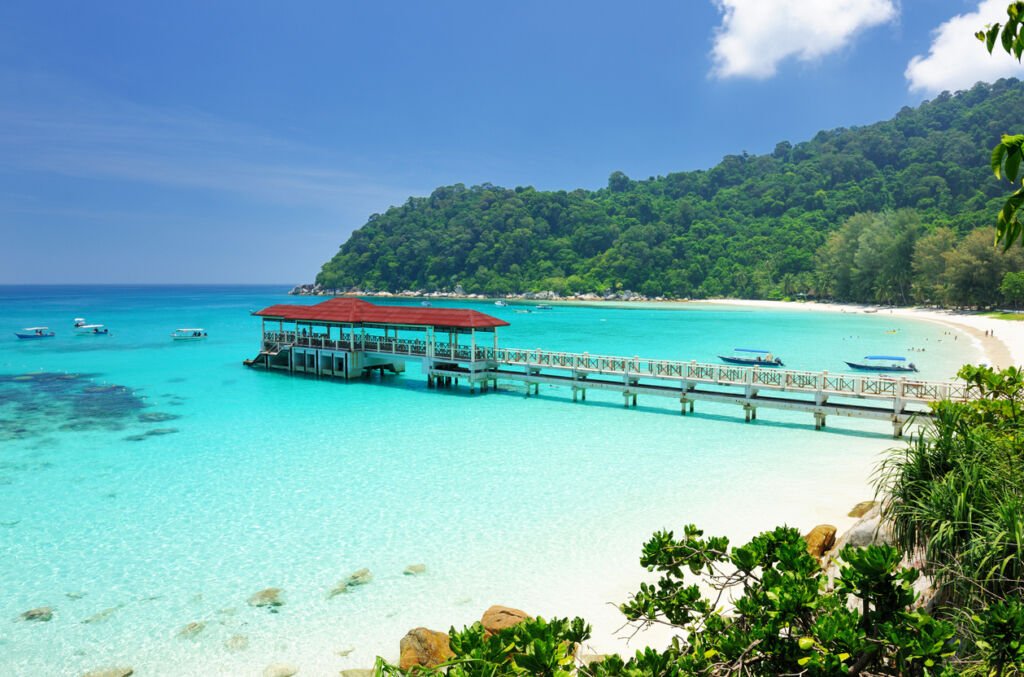 The beautiful beach at Perhentian Islands enchants with powdery sands, kissed by turquoise tides. Swaying palms frame the idyllic scene, inviting tranquil seaside reverie.
