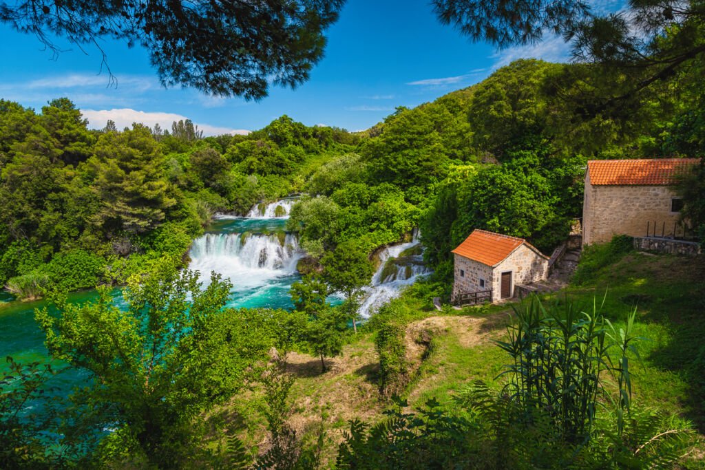 Krka National Park, a Mediterranean haven for hiking and excursions, where crystal-clear waters cascade down limestone terraces, cradling lush greenery in a tranquil, natural masterpiece.