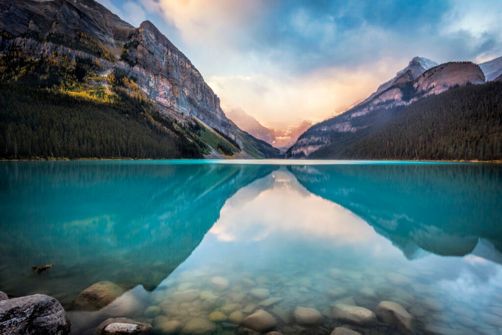 Lake Louise in Banff National Park is a mesmerizing turquoise glacial lake, surrounded by towering snow-capped mountains, lush green forests, and a majestic glacier in the background.