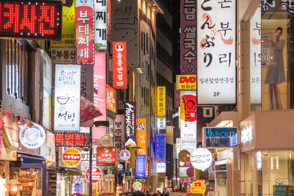 Vibrant neon lights illuminate Myeong-Dong, Seoul, casting a magical glow on bustling streets and lively, eager shoppers.