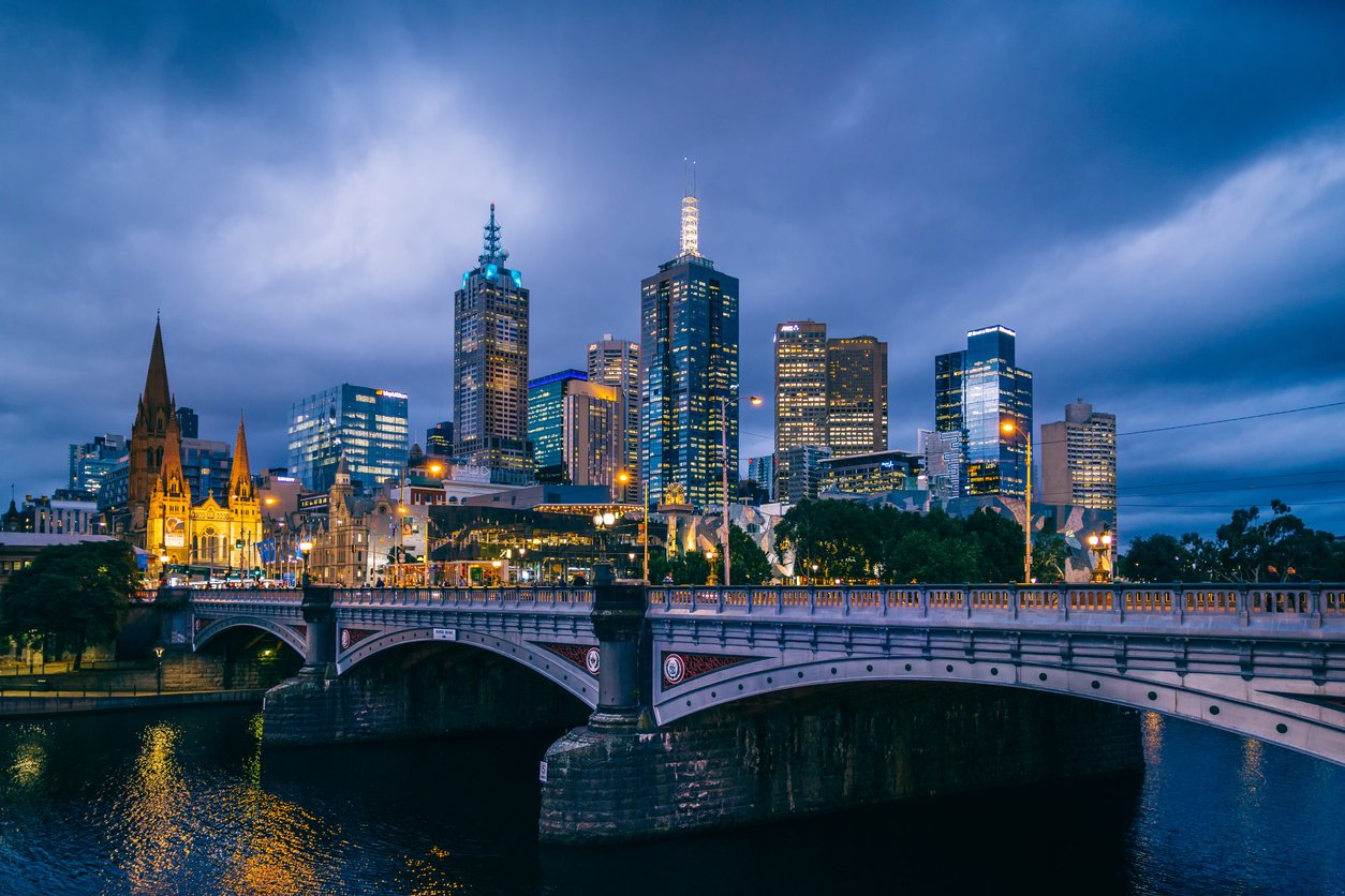 Melbourne's iconic skyline, a dazzling symphony of modern architecture, stretches along the Yarra's south bank, reflecting in the gentle waters, under a captivating, city-lit night sky.