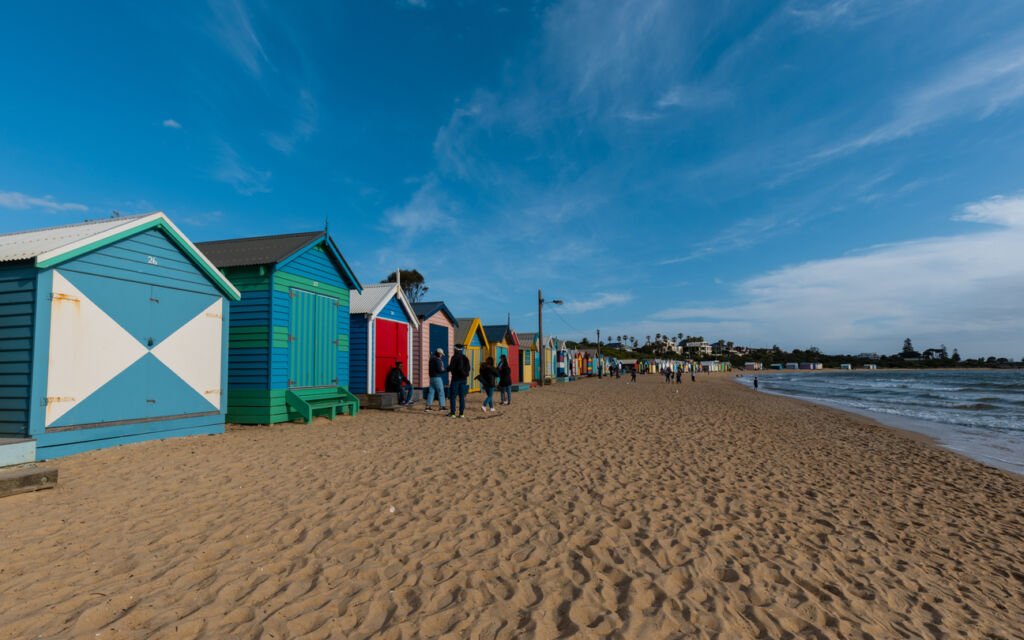 Melbourne, Australia - A kaleidoscope of color graces Brighton Beach during the day. Iconic bathing boxes line the shore, standing as vibrant sentinels against the azure backdrop of sea and sky.