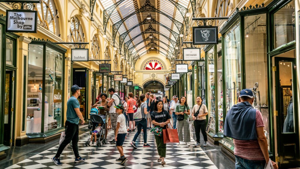 Melbourne's Royal Arcade buzzes with life as a vibrant tapestry of people weaves through the historic space. The intricate architecture frames a lively scene, echoing with the pulse of city energy.