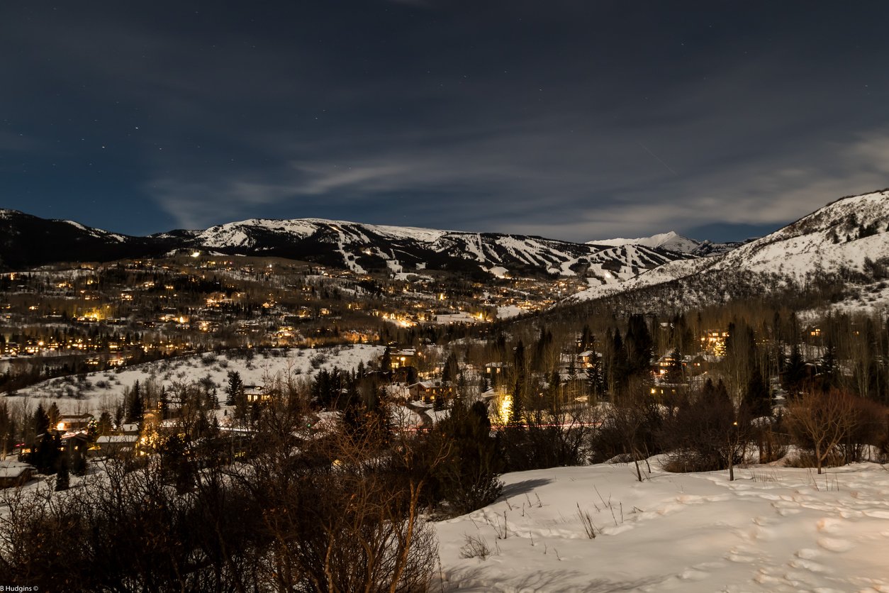 Snowmass Village in Aspen, Colorado, captivates at night. Glowing streets and mountain silhouettes form a picturesque nocturnal scene, blending charm and tranquility under the starlit sky.