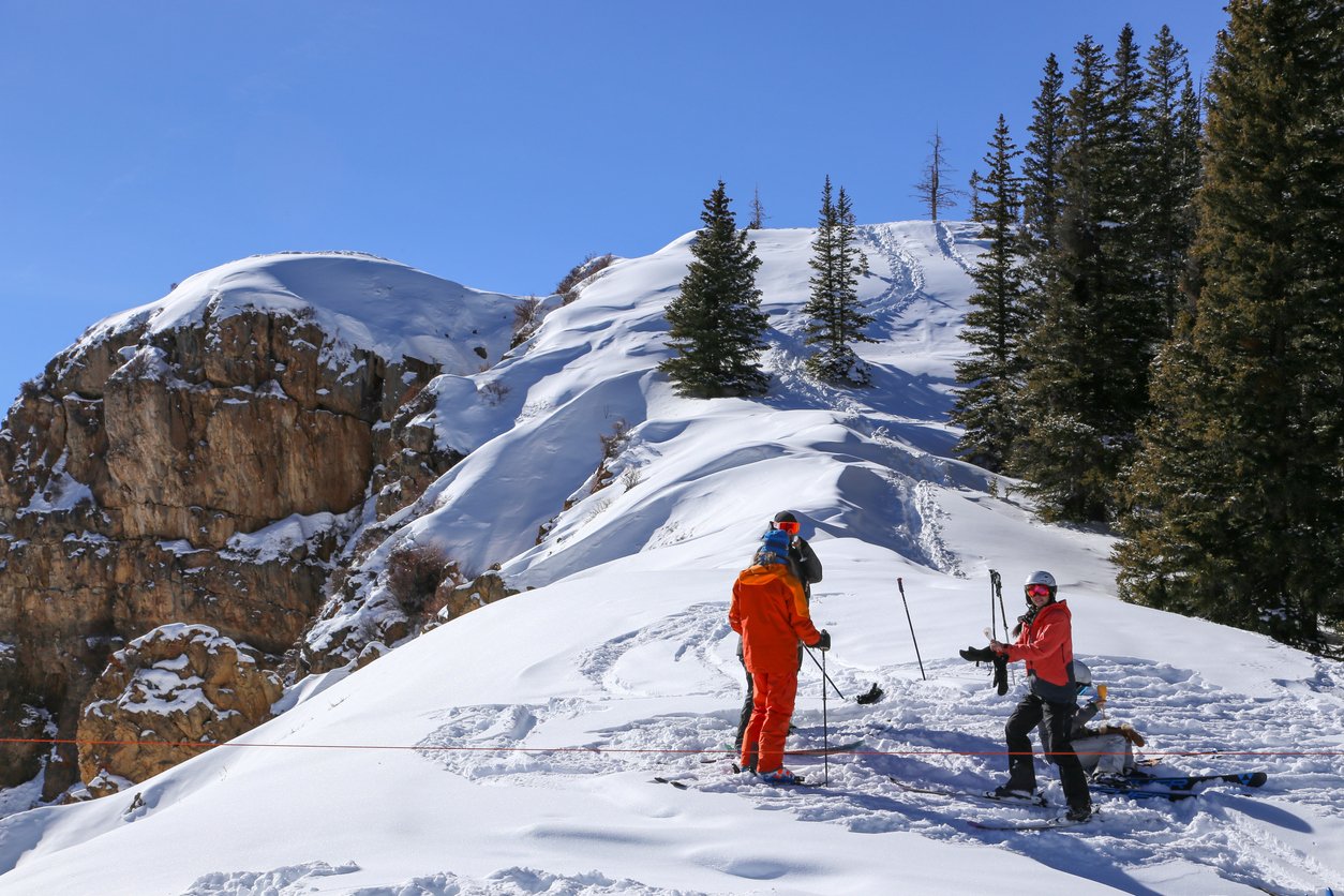 Two daring skiers venture out of bounds in Aspen, Colorado, embracing the thrill of untouched terrain beyond the resort's confines amid the stunning mountainous backdrop.