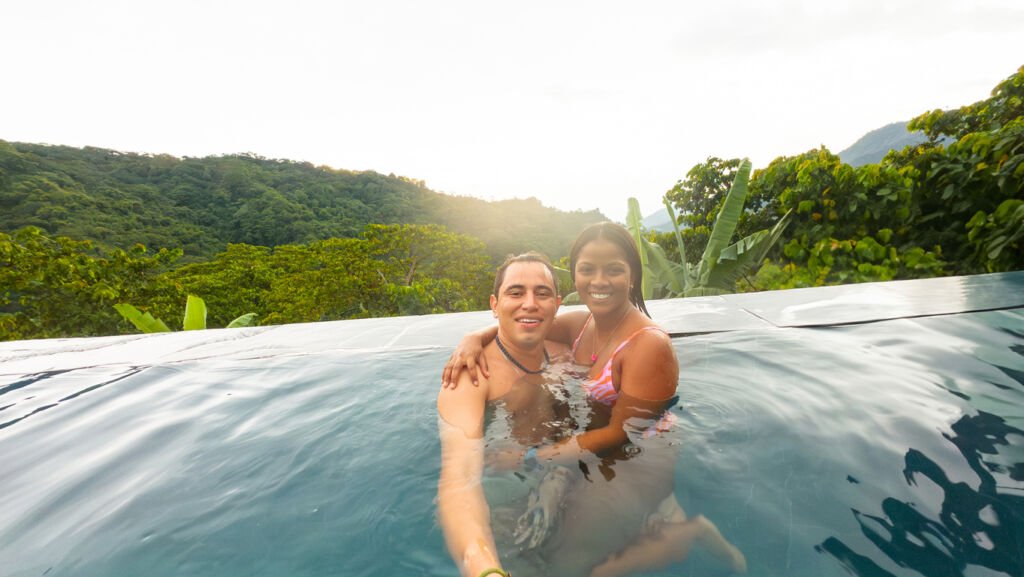 Amidst the lush tranquility of Minca, Colombia, a couple finds bliss by the pool. Embraced by tropical beauty, their smiles reflect the joy of a serene escape.