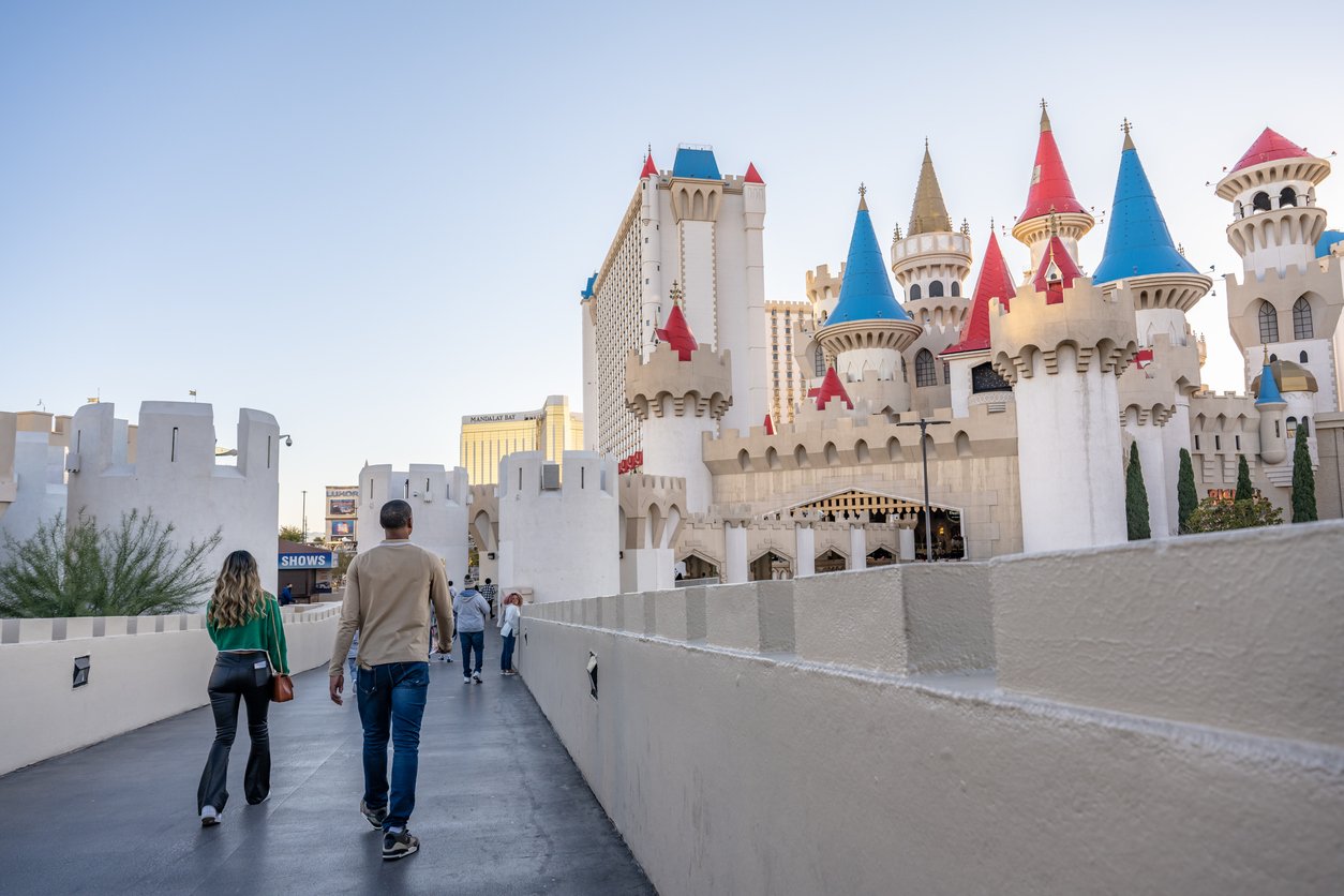 In the dazzling atmosphere of the Las Vegas Strip, a young couple explores the pedestrian bridges surrounding the Excalibur Hotel and Casino, immersed in the vibrant energy of the iconic entertainment district.