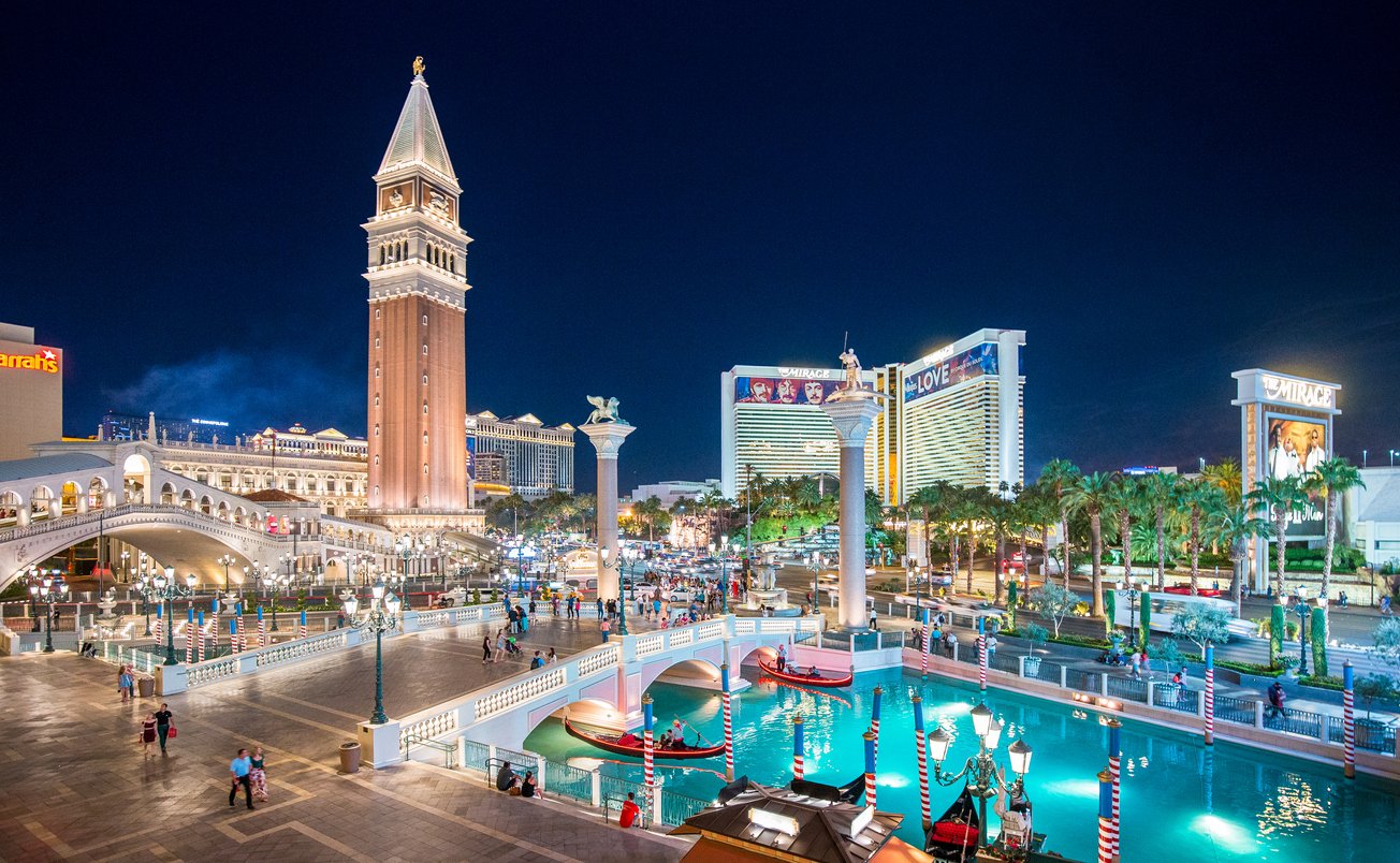 Las Vegas dazzles at night, featuring Downtown's iconic Strip and the radiant brilliance of The Venetian Resort Hotel. A vibrant spectacle in the Nevada sky, epitomizing the city's allure.