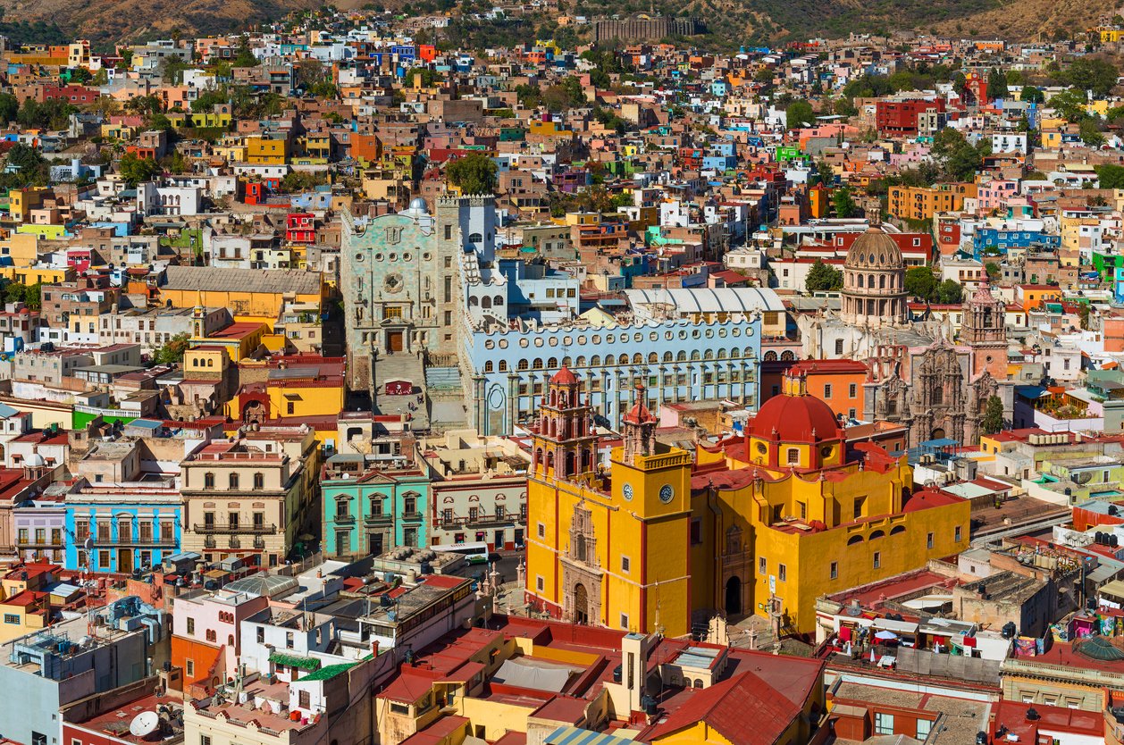 Guanajuato City skyline unfolds in a captivating aerial view. The yellow Basilica of Our Lady of Guanajuato commands attention against a backdrop of vibrant, colorful houses in Mexico.