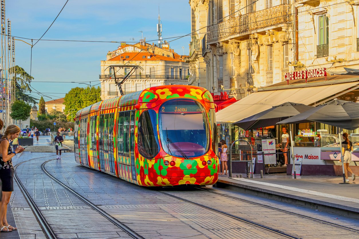 Montpellier, August 23, 2022: A vibrant modern tram glides through the city's heart, adding a splash of color to the urban canvas, seamlessly blending contemporary transportation with historic charm.