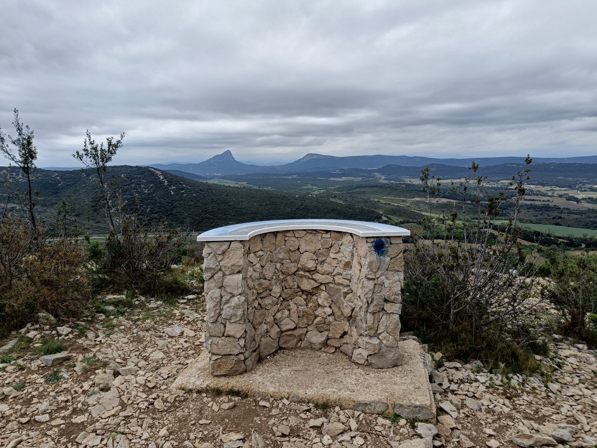 Perched before Pic Saint-Loup and l'Hortus, the orientation table unveils a panorama of untamed beauty. Rolling hills embrace rugged peaks, a testament to nature's grandeur near Montpellier, France.