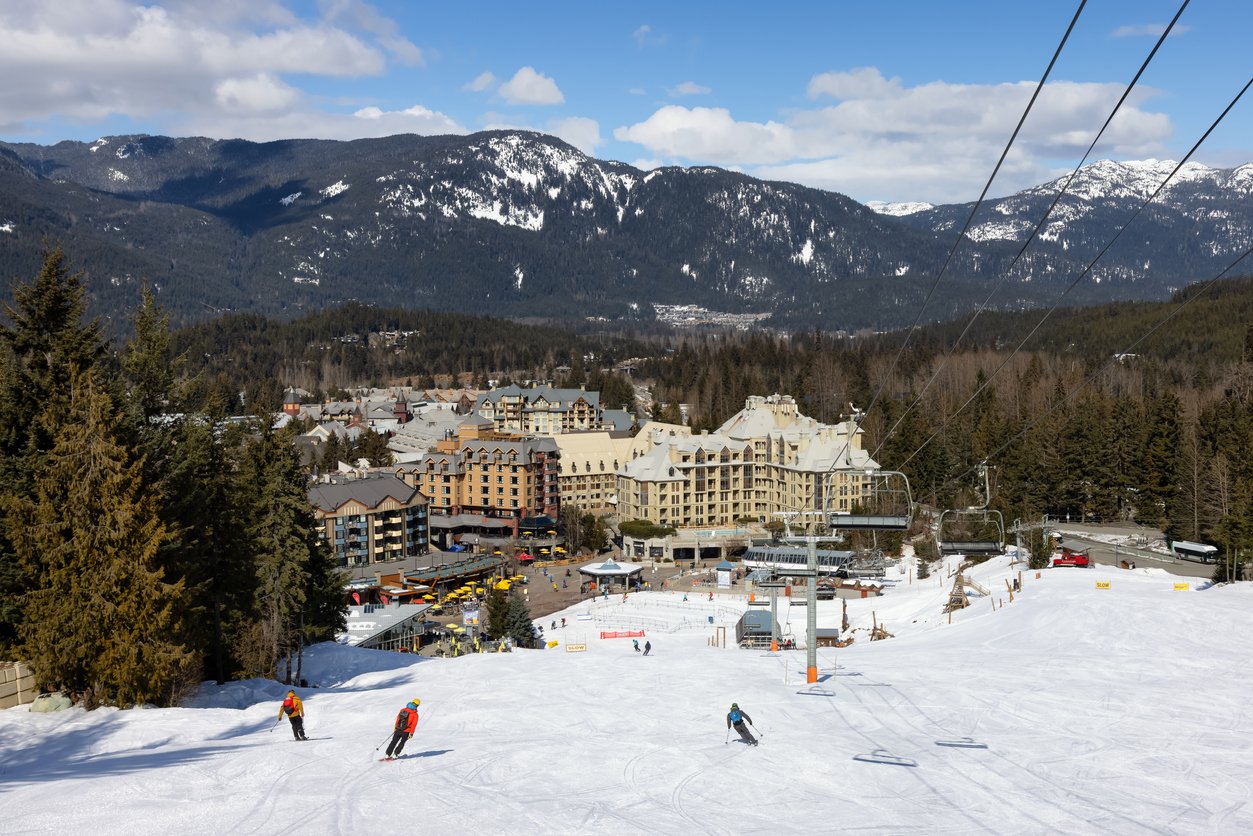 In Whistler, British Columbia, Canada, a charming village unfolds with alpine chalets and vacation homes. Towering mountains frame the scene, inviting winter enthusiasts to a picturesque haven at this renowned ski resort.