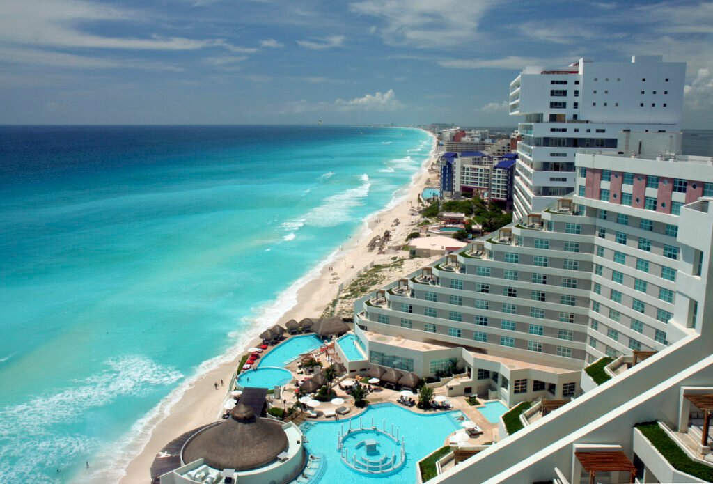 Cancun's coastal splendor unfolds in this aerial view, showcasing a tapestry of resorts seamlessly blending with the turquoise waters and golden beaches. A captivating panorama of leisure and luxury on the Mexican coastline.