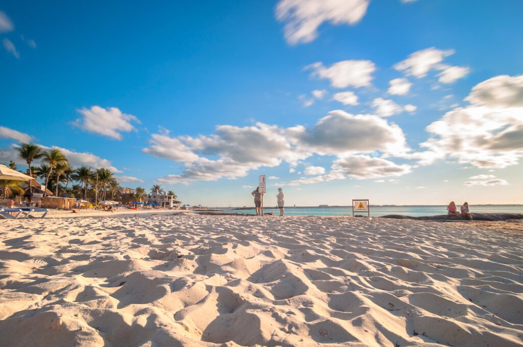 Isla Mujeres, Mexico: A serene moment captured through a long exposure, revealing tourists relishing the sunset on the renowned Playa del Norte beach. This idyllic island lies 8 miles northeast of Cancún in the Caribbean Sea.