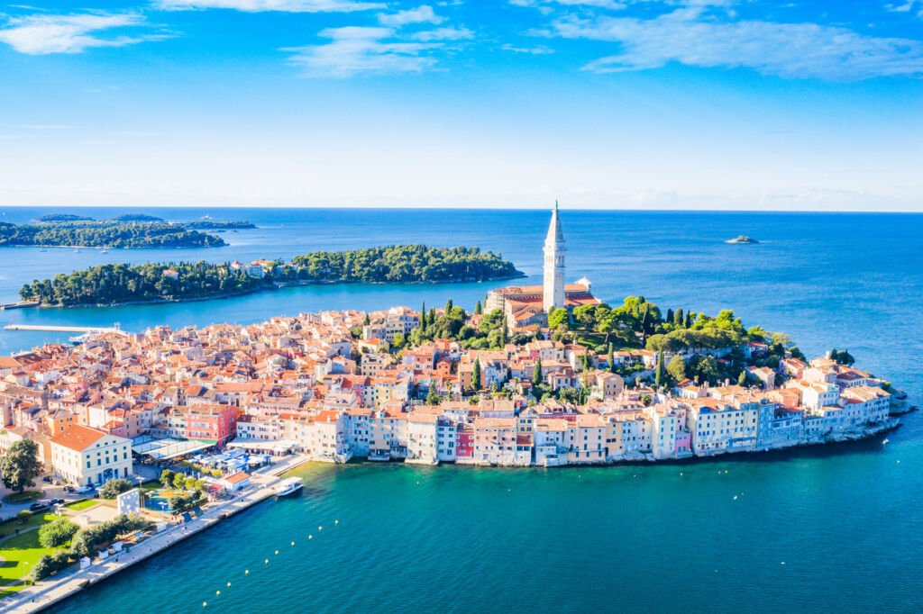 A panoramic aerial vista showcases the stunning blue Adriatic coast in Istria, Croatia. Rovinj's old town stands as a picturesque gem, blending seamlessly with the coastal beauty of the Adriatic.