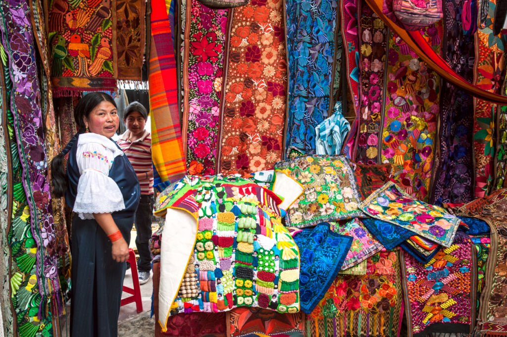 In Otavalo, Ecuador, indigenous women, adorned in traditional clothing, skillfully display and sell their handwoven products on the bustling market. This vibrant scene captures the rich cultural heritage of Ecuadorian Indian ethnicity.