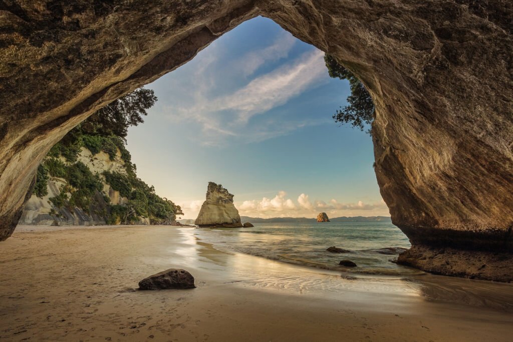 Located north of Hahei on the Coromandel Peninsula, Cathedral Cove in Mercury Bay, North Island, New Zealand, captivates with its stunning natural arch, pristine beaches, and crystal-clear waters.