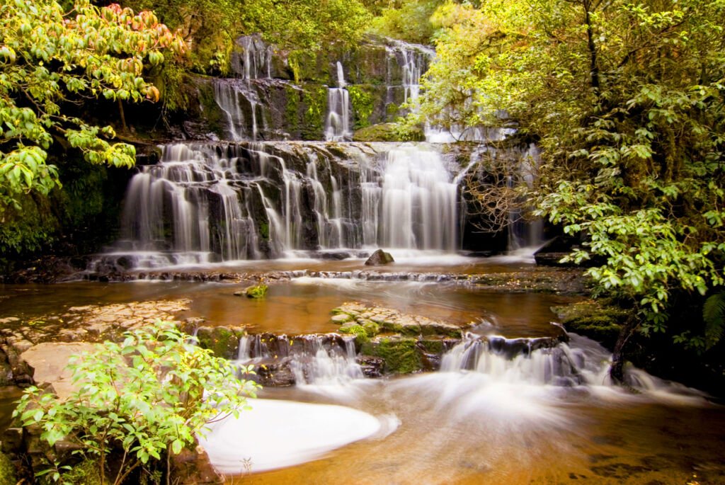 Discover the mesmerizing Purakaunui Cascades waterfall in the Catlins, South Island, New Zealand. Nature's masterpiece, the falls cascade gracefully in a serene setting, offering a tranquil escape in the heart of the Southern Hemisphere.